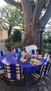 蒙法维伯尔尼与米歇尔住宿加早餐旅馆的桌子,桌子上布满了蓝色的桌布,椅子在树下