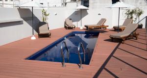 布宜诺斯艾利斯ARC阿雷纳莱斯套房公寓的游泳池位于带椅子和遮阳伞的甲板上