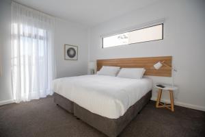 Whitemark岛上公寓的卧室设有一张白色大床和一扇窗户。
