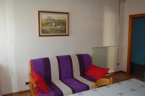 苏坎Andron的客厅配有带红色枕头的紫色沙发