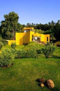 莫雷利亚Hotel Casa en el Campo的坐落在郁郁葱葱的绿色庭院顶部的黄色房子