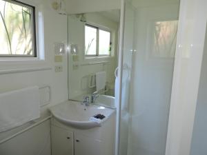 欧尼罗亚怀赫科岛蓬加山林小屋的白色的浴室设有水槽和淋浴。
