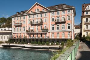 巴登Limmathof Baden - Historisches Haus & Spa的河边一座大型粉红色建筑