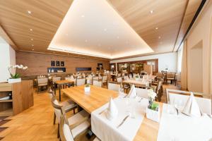 阿尔特多夫胡夫利酒店的餐厅设有木桌和白色的桌椅