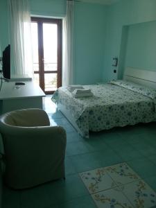 卡梅罗塔码头Albergo Riccio的卧室配有床、椅子和窗户。