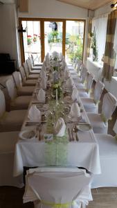 多瑙河畔韦尔特Gasthof Pflamminger的一张长桌子,上面有白色的桌子和白色的椅子