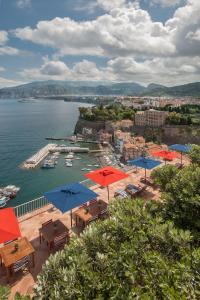索伦托梅森米纳维塔酒店的海港景,配有桌子和伞