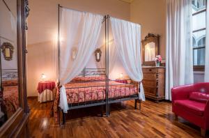 佛罗伦萨托瑞古尔法阿奇亚奥里豪华酒店的一间卧室配有天蓬床和红色沙发