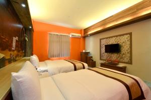 台中市西悠饭店台中店的橙色墙壁的酒店客房内的两张床