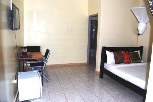 GuluDich Comfort Hotel - Main Branch的一间卧室配有一张床、一张桌子和一张书桌