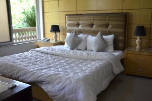 伊斯兰堡格法斯旅馆的卧室配有一张带白色床单和枕头的大床。