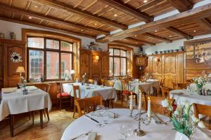 奥特罗特拉米弗里茨餐厅酒店的餐厅设有白色的桌椅和木制天花板。