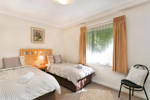 珀斯Perth Short Stays的一间卧室设有两张床、一个窗口和椅子