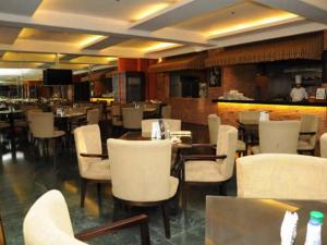 马尼拉塞提特托尔酒店的一间设有白色桌椅的餐厅和一间酒吧