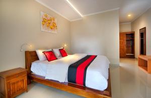 坎古坎古普里别墅酒店的一间卧室配有一张带红色枕头的大床