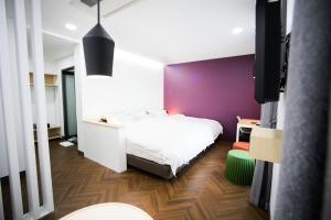 光州葡萄酒精品酒店的卧室配有白色的床和紫色墙壁