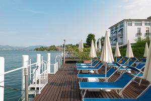 西尔米奥奈伊登酒店的水面上带椅子和遮阳伞的码头