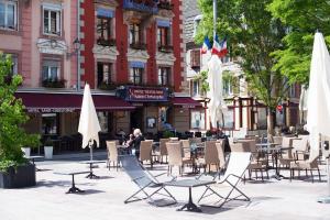 贝尔福Hotel-Restaurant St-Christophe的城市街道上的一组桌椅和遮阳伞