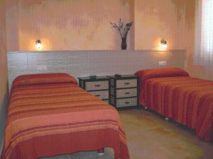 阿尔贝尔达德里瓜德里瓜山谷旅馆的卧室内的两张床,配有红色和橙色床单