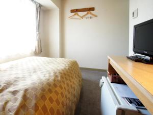 长野长野潮流酒店的一间卧室配有一张床和一台平面电视
