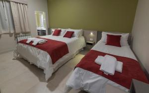 罗卡将军市Estepa Hotel的一间卧室配有两张红色和白色床单