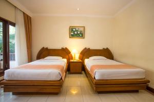 沙努尔帕瑞吉塔度假酒店及水疗中心的一间卧室配有两张床和一盏灯。
