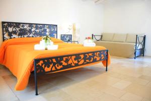 阿尔贝罗贝洛Corte Trullo Sovrano B&B的一张带橙色棉被和沙发的床