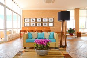 坎皮纳斯Vitória Hotel Express Dom Pedro的客厅配有蓝色的沙发和鲜花