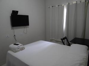 北茹阿泽鲁Pousada Vó Otília的卧室配有白色的床和平面电视。