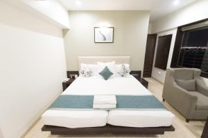 孟买Hotel Le Grande - Mumbai International Airport的一间卧室配有一张大床和一把椅子