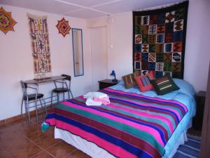 圣佩德罗·德·阿塔卡马坎普基地旅舍的一间卧室配有一张带彩色毯子的床