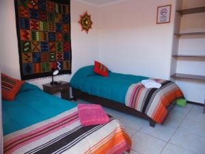 圣佩德罗·德·阿塔卡马坎普基地旅舍的一间卧室配有两张带彩色毯子的床