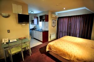 基督城雅典娜汽车旅馆的一间卧室配有一张床铺和一张桌子,还设有一间厨房