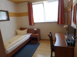 腓特烈港Hotel Heuschober的一间小卧室,配有一张床、一张书桌和一个窗户
