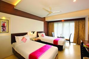 提喀迪Holiday Vista Luxury Hotel and Spa, Thekkady的酒店客房设有两张床和窗户。