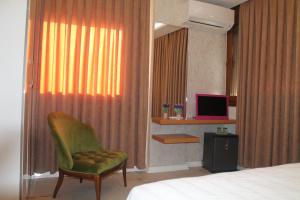 迪基利Lila Butik Hotel Dikili的一间卧室配有一张床、一张绿色椅子和电视。