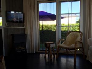 霍勒姆Chalet Zilt Ameland的客厅配有椅子和滑动玻璃门
