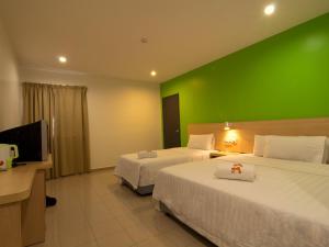 玻璃市港口玻璃市瓜拉T酒店的酒店客房设有两张床和绿色的墙壁。