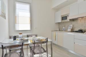 博洛尼亚UR-NEST Vestri - Golden Suite的厨房配有白色橱柜和桌椅