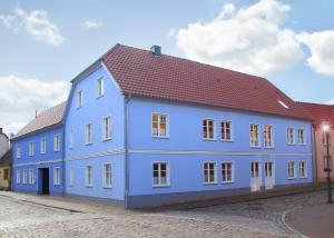 勒伯尔Ferienwohnungen Malow的一条蓝色的建筑,在街上有红色的屋顶