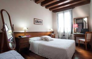 巴萨诺－德尔格拉帕阿尔城堡酒店的一间卧室配有一张床、梳妆台和镜子