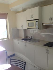 卧龙岗贝尔蒙都公寓的白色的厨房配有水槽和微波炉