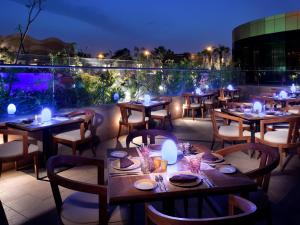 利雅德voco - Riyadh, an IHG Hotel的晚上在庭院里设有桌椅的餐厅