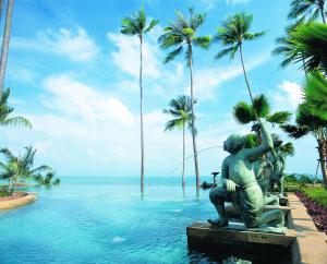 波普托Anantara Bophut Koh Samui Resort的棕榈树泳池中间的雕像