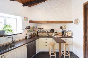 圣米格尔德阿沃纳Sansofi Guesthouse的厨房配有水槽和带凳子的台面