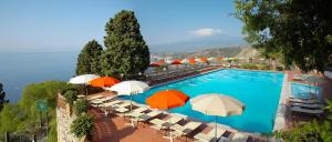 陶尔米纳迪奥多罗别墅酒店的一个带遮阳伞和椅子的大型游泳池