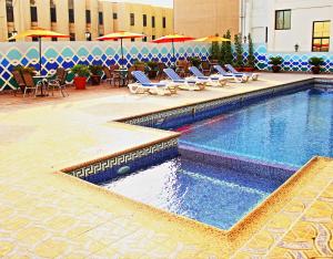 麦纳麦巴林国际酒店的一个带桌椅和遮阳伞的游泳池