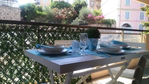 戛纳Appartement proche mer et gare的阳台上配有带盘子和玻璃杯的白色桌子