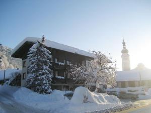 KirchbachGasthof-Pension Golob的一座被雪覆盖的建筑,背后是钟楼