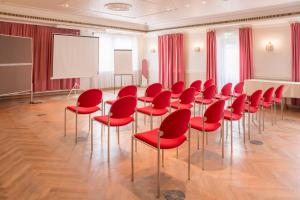 唐格明德坦格尔明德施沃泽阿德勒酒店的一间会议室,配有红色椅子和白色板